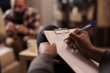 Male psychologist taking notes at couple therapy session